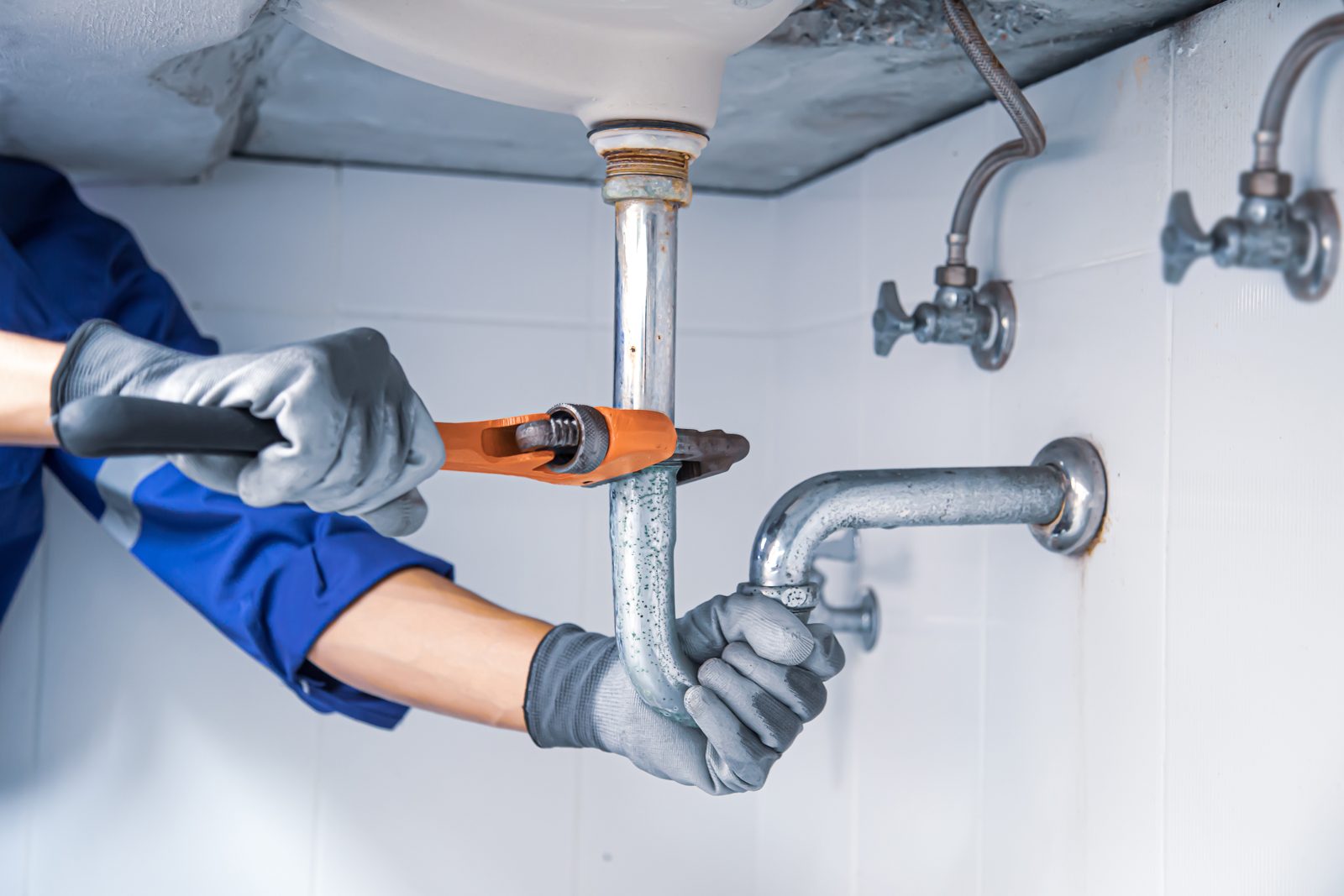 Plumber repairing a pipe with a wrench